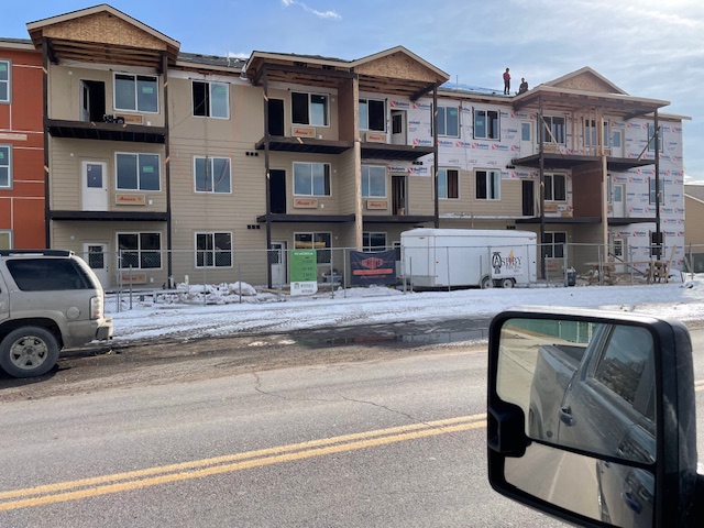 Advanced Custom Builders crew framing a multi-story apartment building in winter with snow on the ground in Missoula