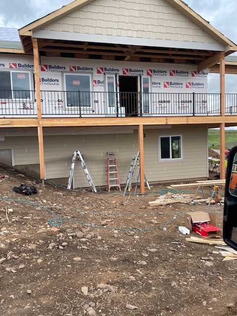 Rear exterior of a custom home built by Advanced Custom Builders with a covered upper deck and house wrap near Missoula