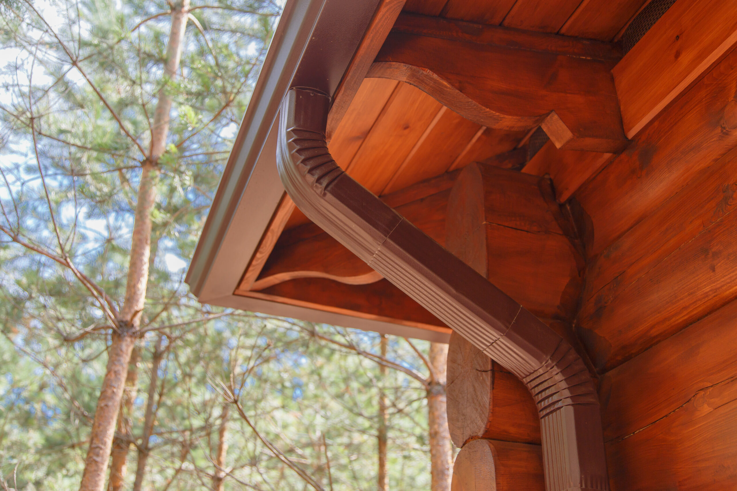 Log cabin with brown metal gutters and downspout